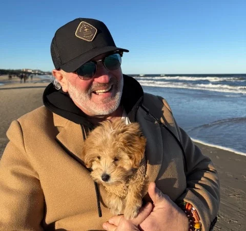 Oliver Kadow mit Suki versteck im Mantel am Strand